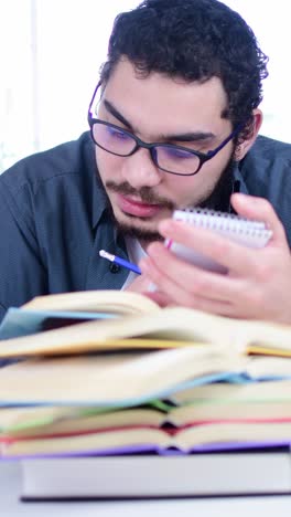 diligent student taking notes surrounded by books