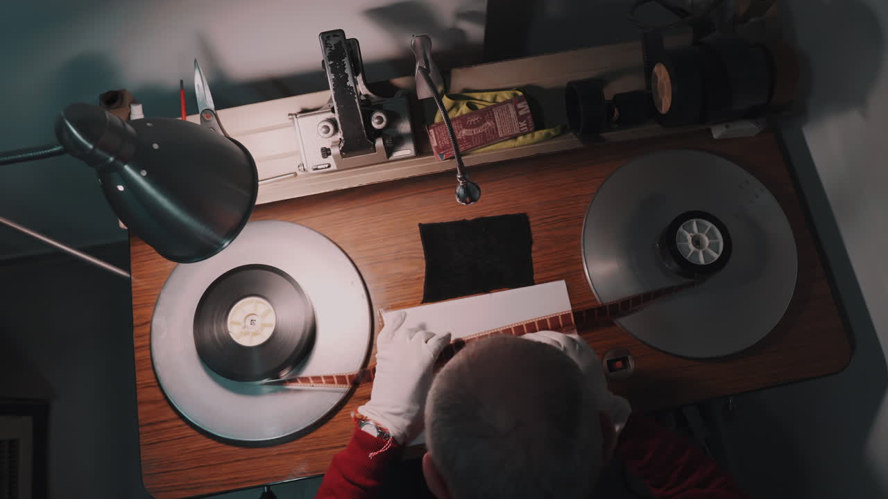 A man working at a film studio, works with old film strip.