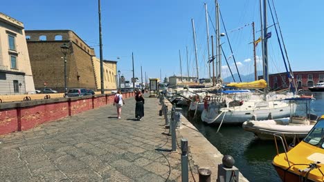 people walking by boats in naples harbour