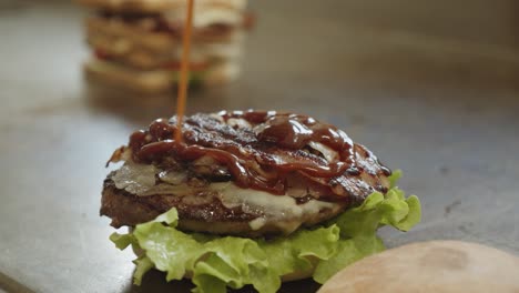 pouring tasty savoury sauce on succulent grilled burger, fast food restaurant,