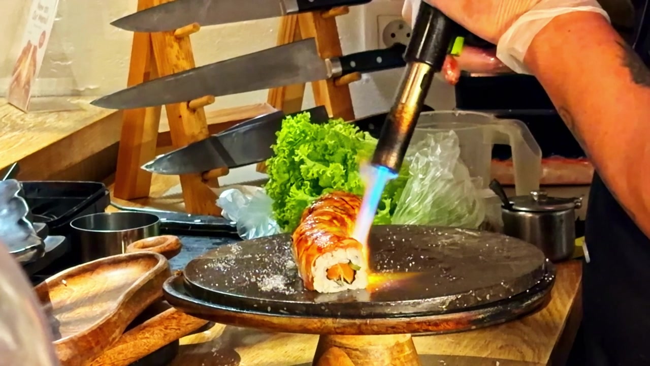 Static Shot of Chef Torch Searing Sushi Roll, Capturing Culinary Craftsmanship