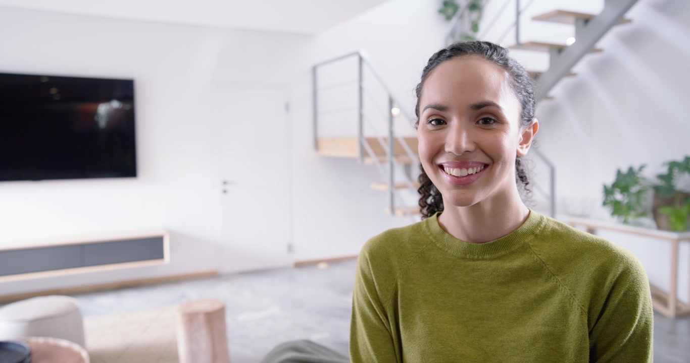 Donna che reagisce alla telecamera che si avvicina, girandosi, sorridendo e poi ridendo in soggiorno con le scale.