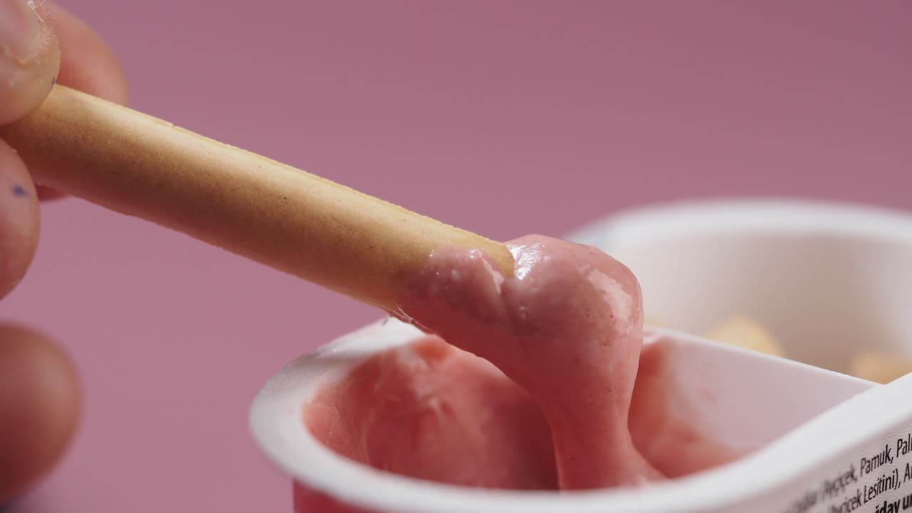 Close-up of Biscuit Stick Dipping into Pink Creamy Yogurt