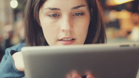 mujer usando una pantalla táctil de una tableta en un café