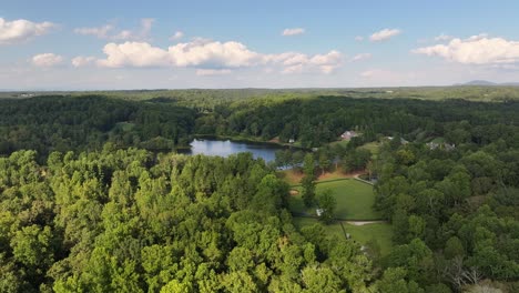 Drone-shot-of-green-country-farm-lake-and-horse-riding-field-in-the-hills-of-Alpharetta,-Polo-Club-and-outdoor-event-destination-in-the-middle-of-forest