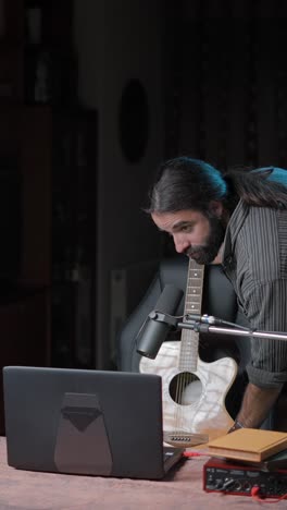 musician preparing acoustic guitar and recording equipment in studio