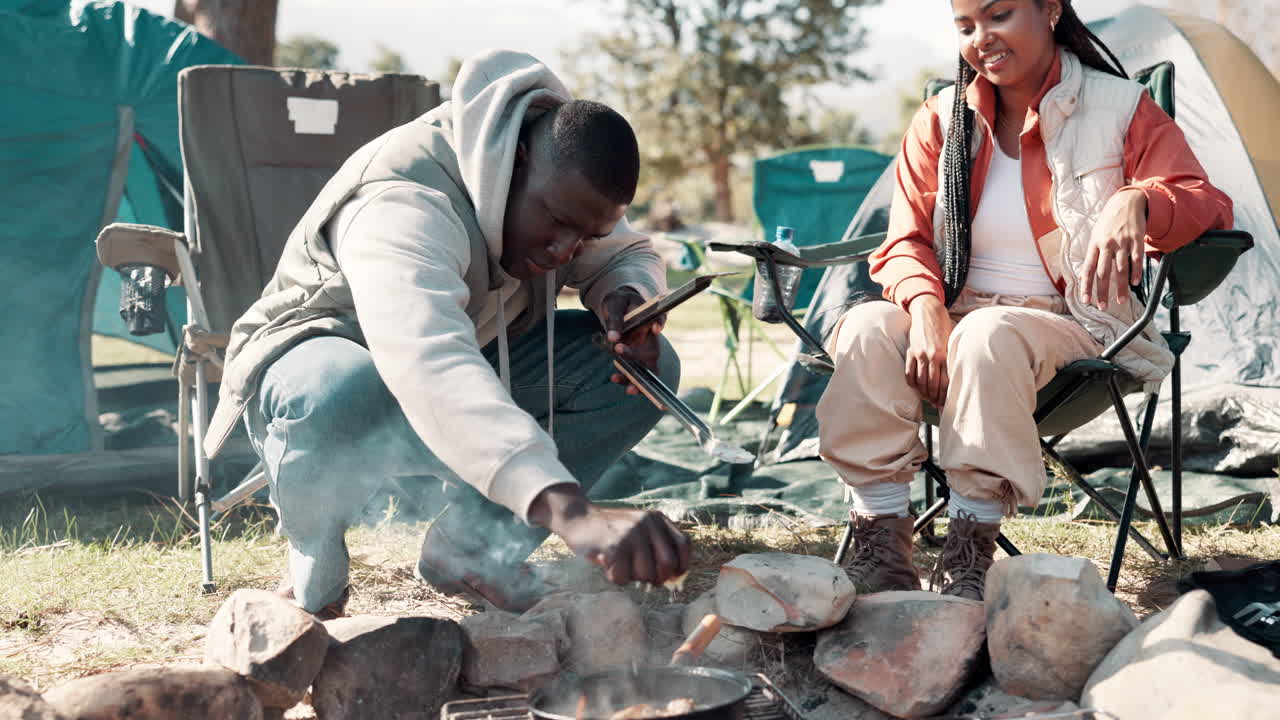 Couple camping and cooking food over a campfire