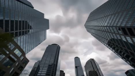 dramatic urban skyline under overcast skies: a glimpse of modern architecture featuring tall glass buildings reflecting cloudy atmosphere