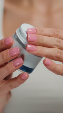 woman opening a jar of skin cream