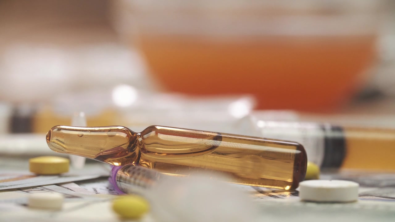 Primo piano di fiala medica, compresse, siringhe e denaro.