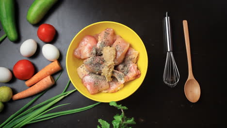 adding ginger garlic paste to chicken pieces in a bowl, spices, black pepper