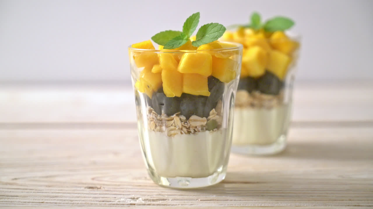 mango fresco casero y arándanos frescos con yogur y granola - estilo de comida saludable