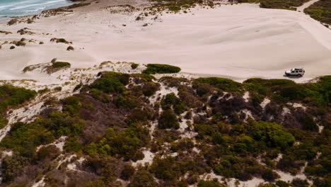 toma aérea, jeep safari entre dunas de arena y el océano