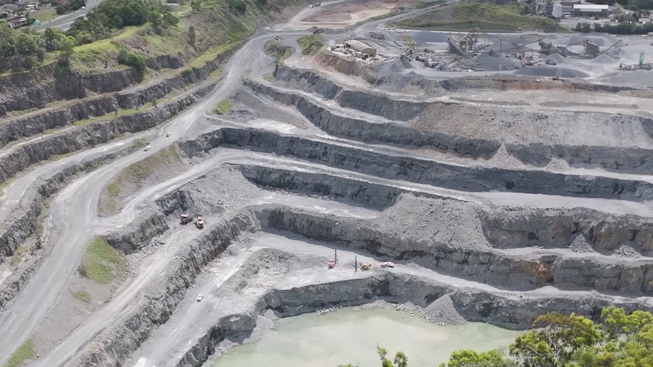 Aerial view of terraced quarry showcasing roads, layers, and surrounding greenery.