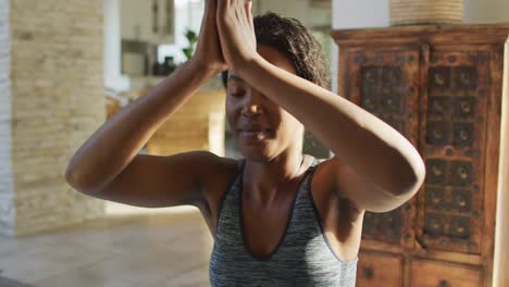 video de una mujer afroamericana relajada practicando yoga en casa