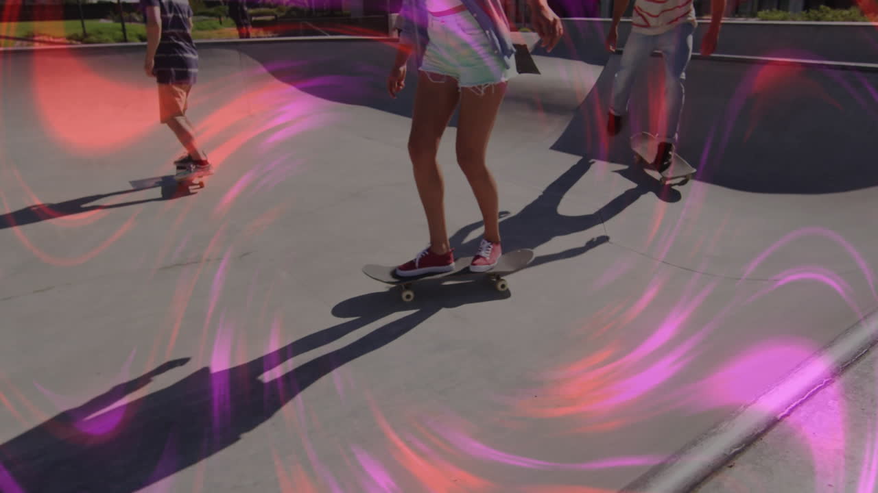 Friends riding skateboards in outdoor skatepark, with technology neon pink and red light swirls