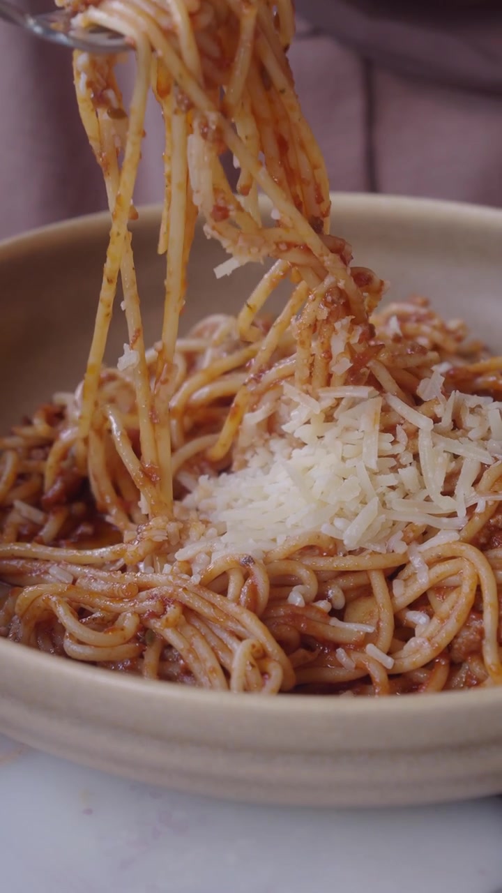 Forchetta che avvolge spaghetti con sugo alla bolognese e Parmigiano