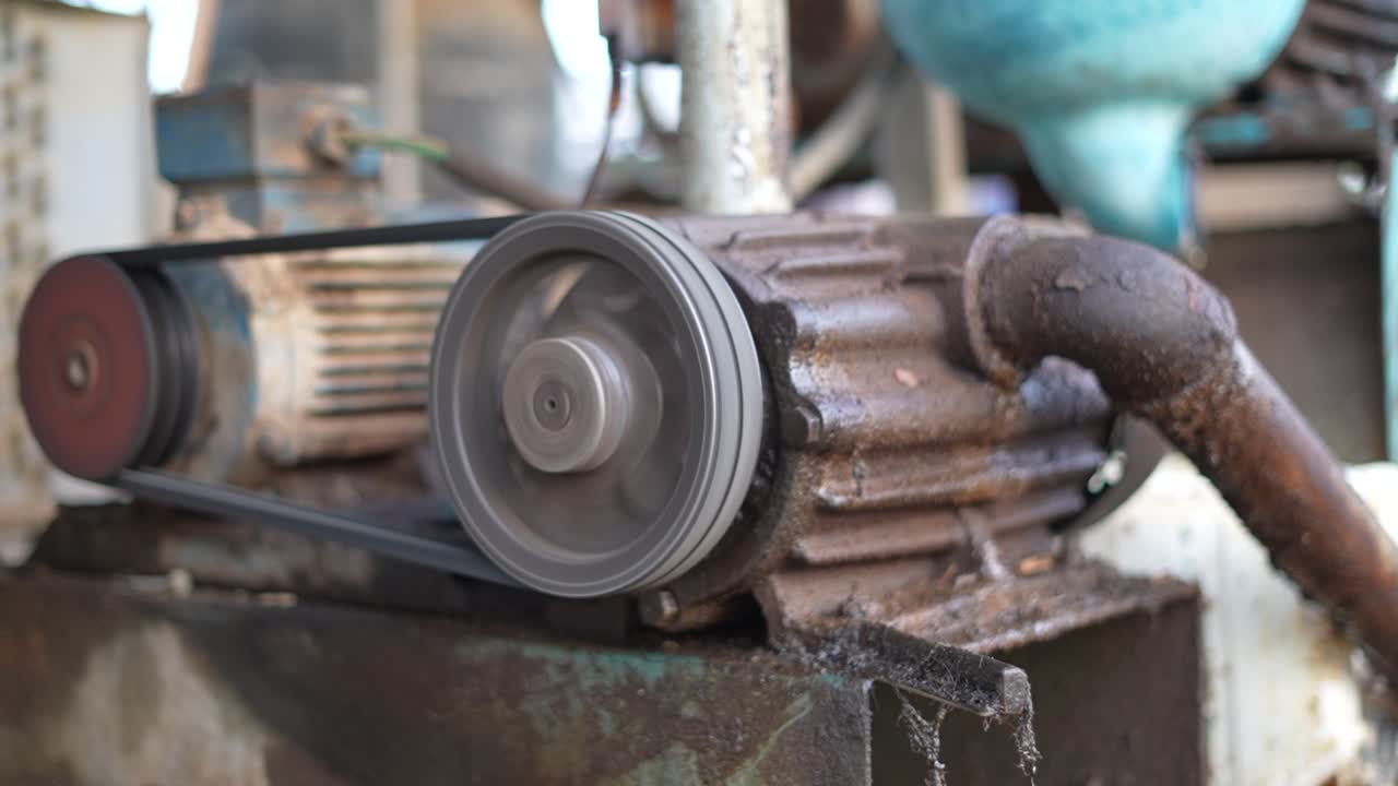 Close-up of rotating agricultural motor with belt drive system inside dairy facility, showing mechanical equipment used in milk production process