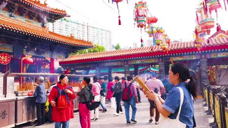 people praying and offering incense at temple