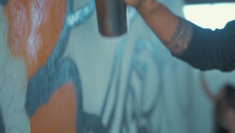 graffiti artist spraying design on wall handheld shot