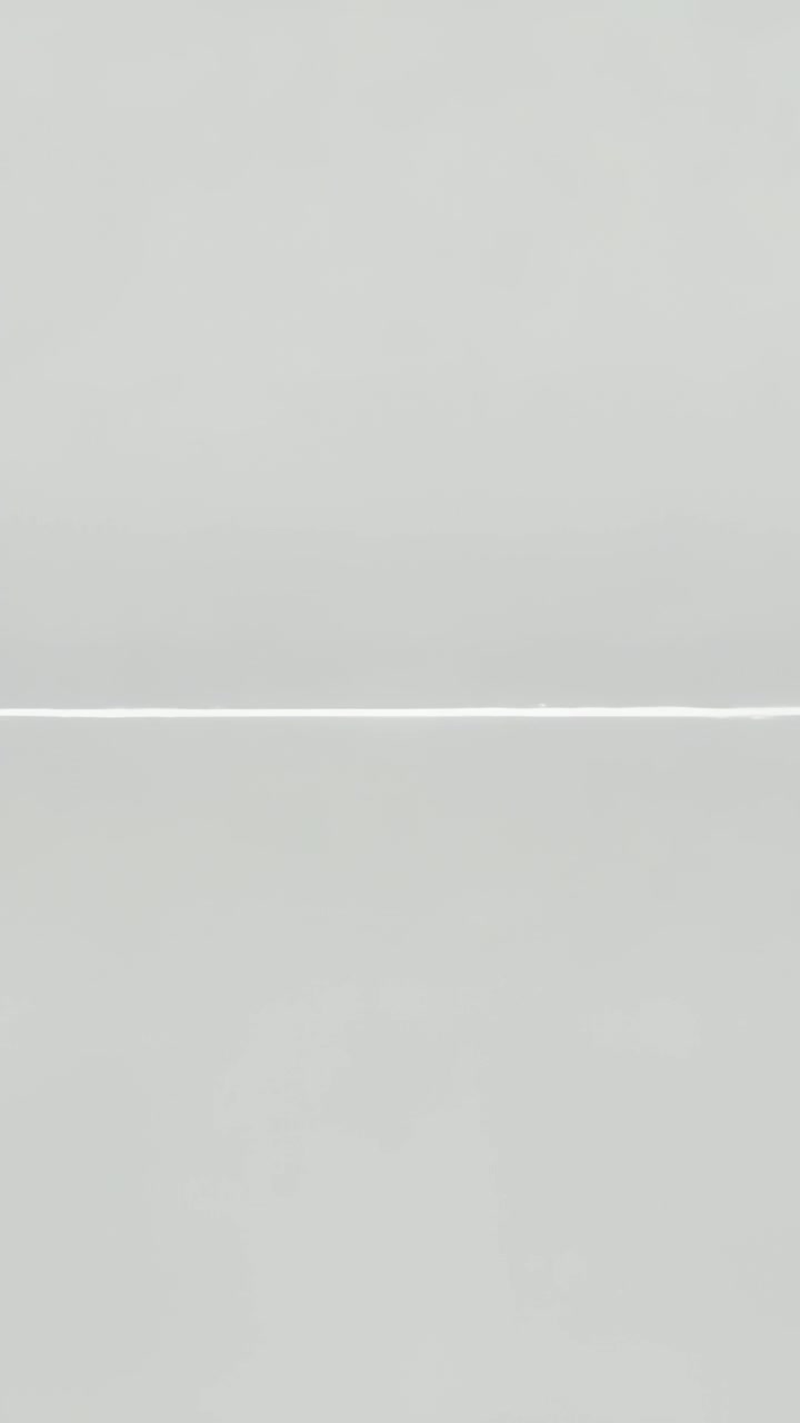 Vertical video: Recording stationary camera capturing light-gray wall with faint seam, no objects
