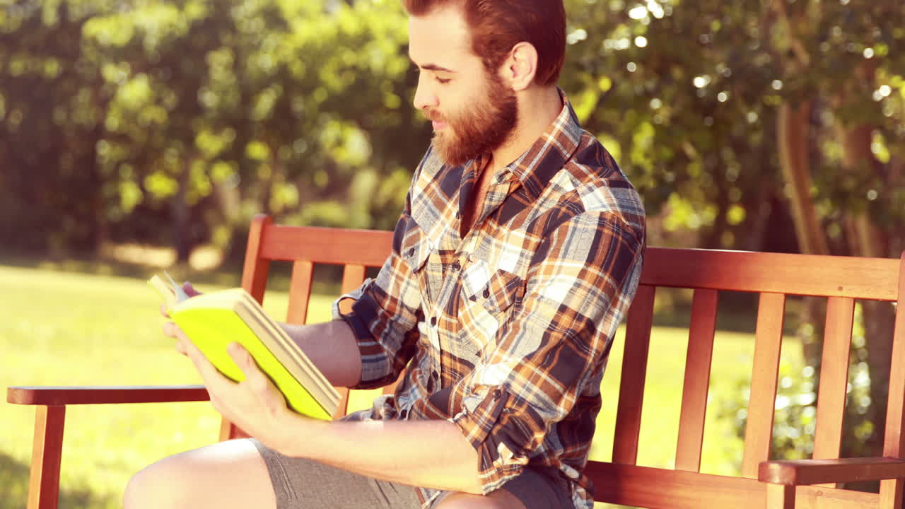 In high quality 4k format handsome hipster reading in the park 