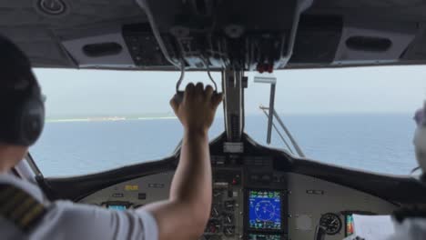 pilots in the cockpit of a sea plane landing near an island