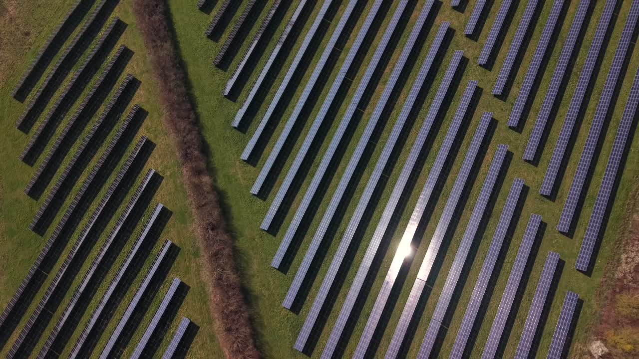 Ripresa aerea dall'alto di un grande impianto fotovoltaico con unità che riflette la luce solare. Giornata di sole nel paesaggio rurale agricolo americano. Inizio primavera negli Stati Uniti. Tema energia verde rinnovabile.