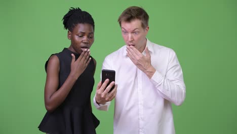 two young multi-ethnic business couple using phone together
