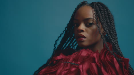 medium closeup of dark skinned woman with full face of makeup wearing layered ruffled dress and beautiful braids