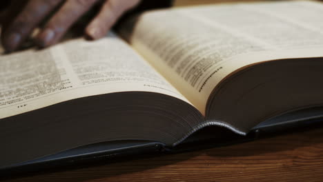 Hands-holding-a-pencil-leaf-through-an-open-book-and-looking-for-information