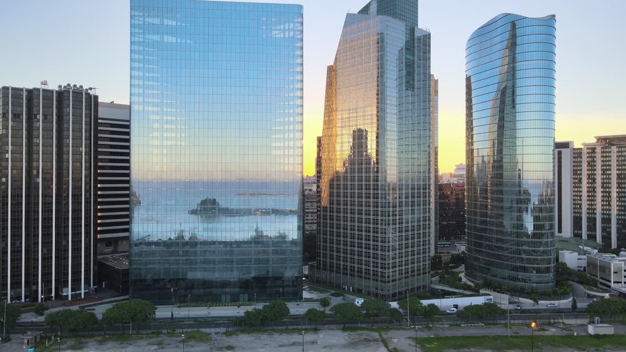toma cinematográfica de modernos edificios de oficinas comerciales con reflejos de vidrio, reflejando el puerto de puerto madero en ventanas de vidrio durante la puesta de sol en el centro de buenos aires, capital de argentina.