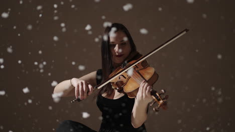 violonchelista tocando el violín en un escenario de estudio con efecto de nieve