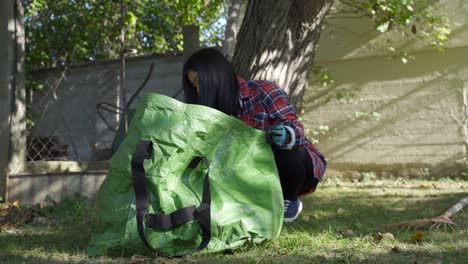 亞洲女孩將乾燥的葉子放到袋子裡,仍然是低角度拍攝