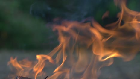 orange flames burning bright and dancing with the wind during dusk, filmed as close up