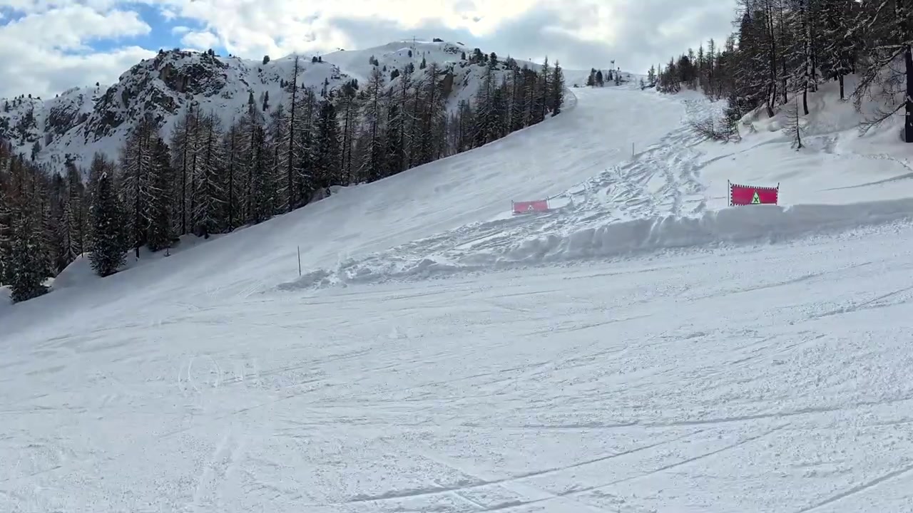 Snowboarder e sciatore che scendono un pendio montano innevato