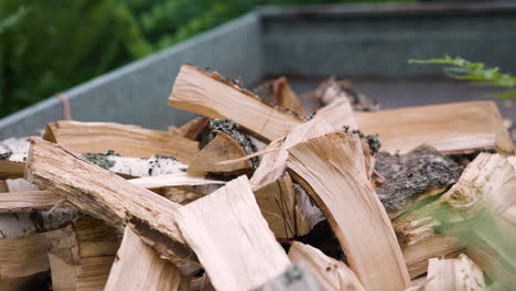 Pieces of birch wood are thrown onto pile of firewood, close slomo pan
