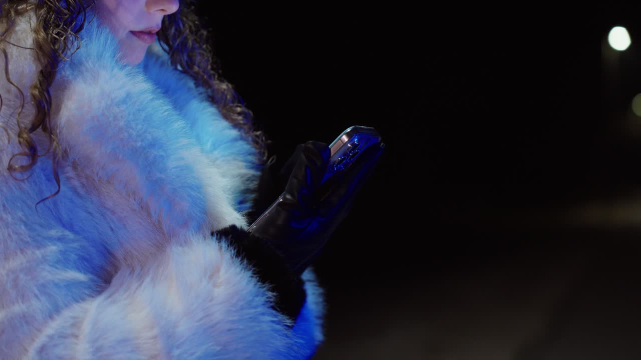 Primo piano cinematografico di una donna in camice bianco che controlla il cellulare in una strada vuota di notte con luci bokeh soffuse. Concept per solitudine, attesa, messaggi a tarda notte e stile di vita digitale moderno