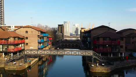 lift up reveal of a tourist taking pictures on footpath bridge with river in residential area, london