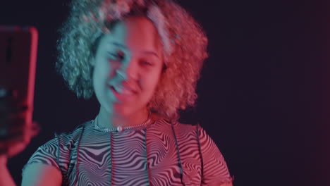 young woman taking a selfie in neon light