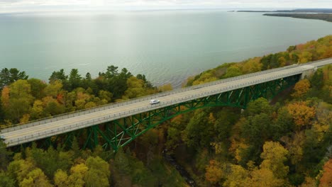 aerial circling shot of green bridge along coast during peak fall foliage