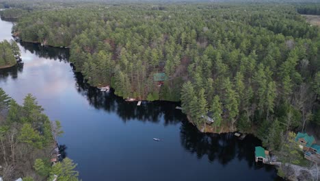 Aerial-view-of-a-canoeist-paddling-on-a-calm-river-winding-through-dense-forest,-surrounded-by-lush-greenery-and-natural-beauty