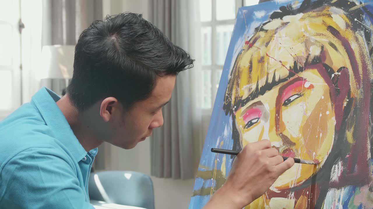 Close Up Side View Of An Asian Artist Man Holding Paintbrush Mixed Colour And Painting A Girl'S Face On The Canvas