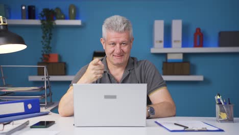 home office worker man makes a trust sign to the camera.