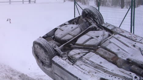 crashed car upside down on the roof after an accident on winter road with snow