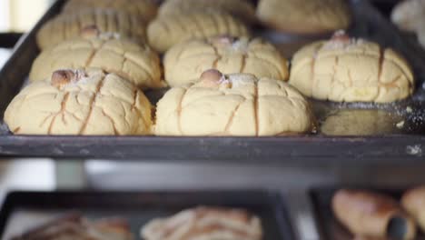 close-up of multiple trays filled with assorted baked pastries cooling on racks inside a bakery