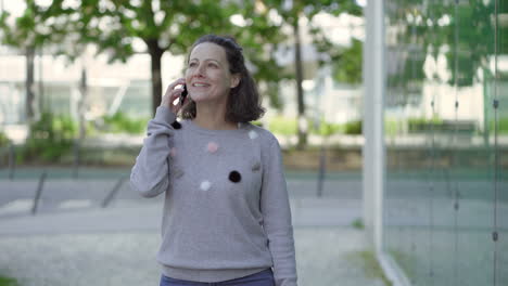 una mujer feliz hablando por teléfono al aire libre.