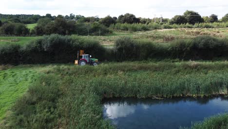 Tractor-En-El-Campo-Recortando-Setos-En-Días-Nublados,-Tiro-De-Seguimiento-Aéreo