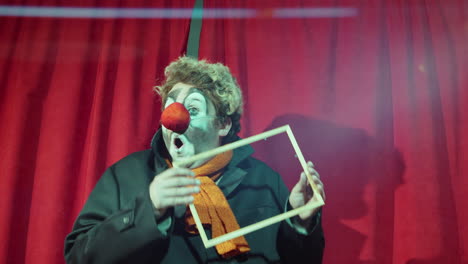 clown performing comedy with wooden frame on stage