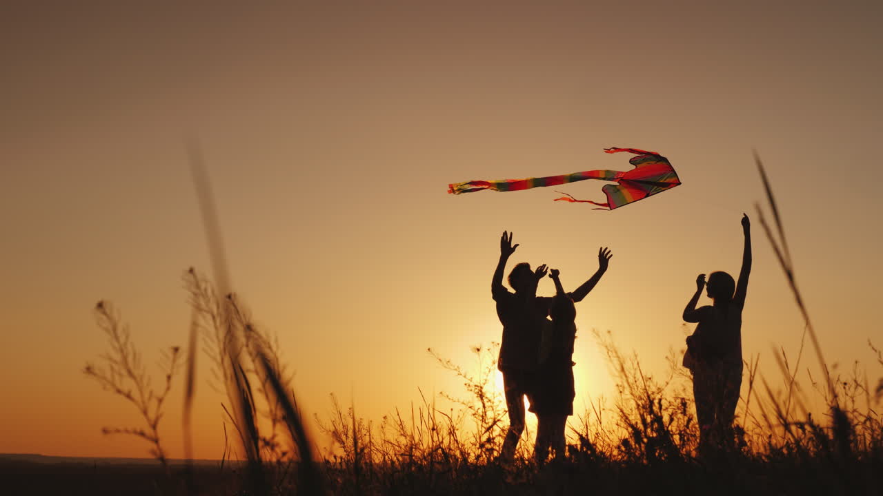 Descarga Gratis Vídeos De Stock De Happy Family Playing With A Kite At Sunset Mom Dad And Daughter Are Happy Together 4K Video. Descarga Clips De Familia